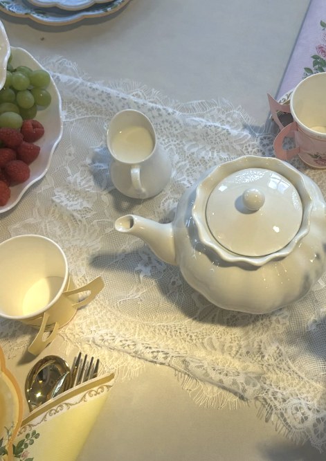 A floral tea party table set with teapot and fruit